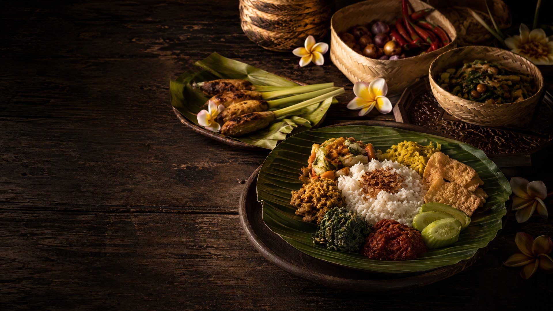 Sajian nasi campur dan sate lilit di atas meja kayu